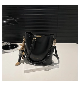 Detail of black bucket bag featuring golden hardware, adjustable strap and rabbit pendant