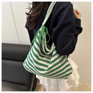 Detail of green and white striped tote bag featuring a decorative lace bow on the side