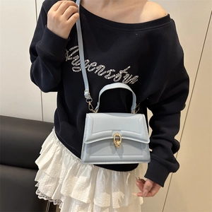 Moderna borsa a trapezio azzurra con chiusura dorata mostrata come borsa a tracolla