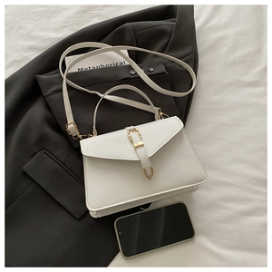 Close-up of structured white leather handbag with golden buckle on professional desk