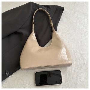 Detail view of glossy beige patent leather shoulder bag with zipper and smooth finish