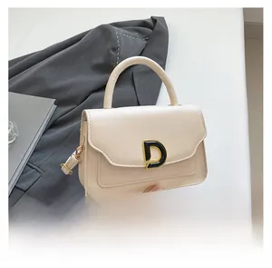 Détail d'un mini sac beige avec un fermoir en métal doré en forme de D très distinctif