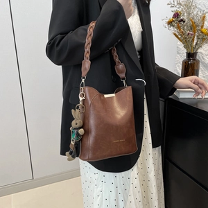 Retro coffee bucket bag with woven handle and bunny charm on black blazer outfit