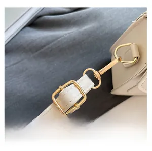 Détail de la bandoulière en cuir blanc avec anneaux en D dorés et boucle en métal doré