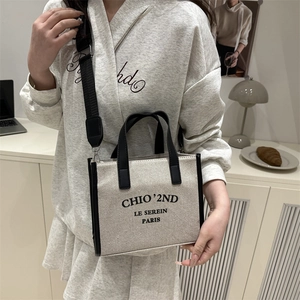 Modern canvas tote bag with black leather trim and crossbody strap for daily fashion