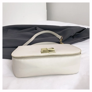 Detail of cream leather flap bag with gold geometric clasp and chain shoulder strap