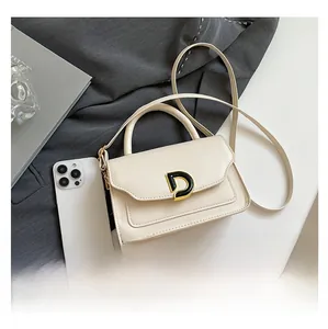 Petit sac carré crème à côté d'un smartphone pour comparer la taille et boucle en D