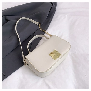 Macro detail of beige leather crossbody bag with elegant gold geometric square clasp lock