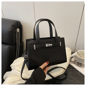 Detailed view of black pebbled leather tote bag with silver turn-lock and shoulder strap
