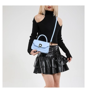 Détail du sac à main bleu clair avec boucle en D dorée et texture en cuir de qualité