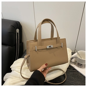 Detail of khaki lychee leather handbag showing silver turn-lock and adjustable strap