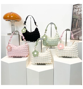 Group view of five colorful bubble fabric underarm bags with floral charms on podiums