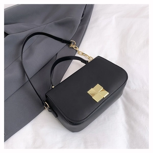 Detail of black leather crossbody bag with vintage gold square buckle and chain strap