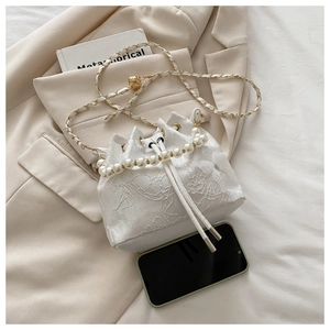 Détail du sac seau en dentelle blanche avec poignée de perles et bandoulière en chaîne