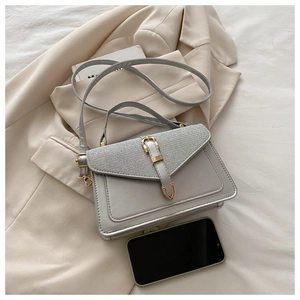 Detail of silver crossbody bag with gold buckle hardware and metallic glitter texture