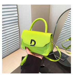 Détail d'un sac à main vert fluo avec une boucle en métal noir distinctive en forme de D