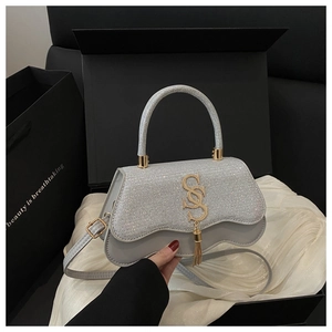 Detail of silver sequin handbag with gold SS logo and elegant metallic tassel accent