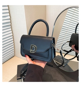 Détail du sac en cuir noir mat avec boucle en D dorée et poignée supérieure élégante