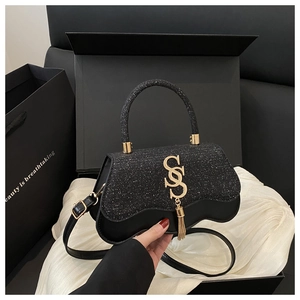 Detail view of black crossbody bag with silver glitter cover and gold SS logo buckle