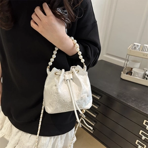 Sac seau blanc texturé avec poignée en perles et bandoulière dans un décor lifestyle