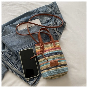 Detail of colorful striped woven mini bag with brown leather strap and fashion label