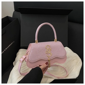 Detail of pink glitter handbag with metallic logo and elegant gold fringe accents