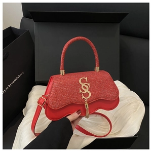 Detail of red crossbody bag with wavy flap, gold SS logo and elegant tassel pendant