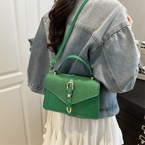 Chic emerald green crossbody bag with sequin detail shown in a stylish home setting