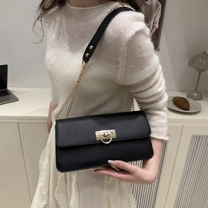 Sac bandoulière noir chic avec chaîne dorée et boucle en D porté par un mannequin