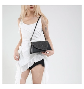 Detail of black envelope crossbody bag featuring a sparkling glitter flap and thin strap