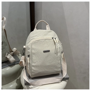 Dettaglio dello zaino in nylon crema con trama plissettata e spallacci regolabili