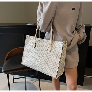 Vue détaillée d'un grand sac cabas blanc avec motif M gris et anses de couleur tannée
