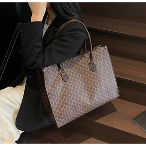Detail of vintage brown monogram tote bag with gold metal hardware and luxury finish