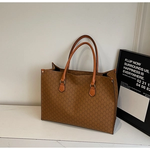 Détail d'un grand sac cabas vintage marron avec monogramme sur une surface en marbre