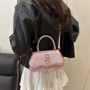 Pink glitter crossbody bag with wave edge and gold S-buckle tassel on a model
