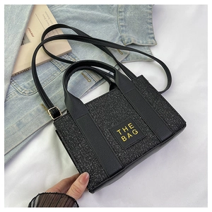 Detailansicht der schwarzen Glitzer Mini-Tasche mit THE BAG Logo auf stylischem Hintergrund