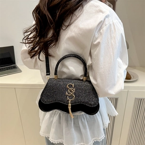 Retro black glitter shoulder bag with gold S logo and fringe in a lifestyle setting