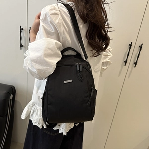 Zaino minimalista in nylon nero con logo metallico e spalline regolabili su modello
