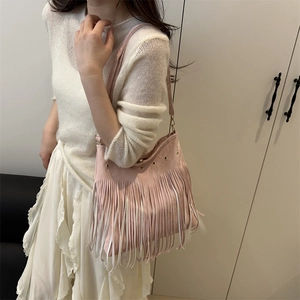 Sac à bandoulière bohème rose à franges avec œillets métalliques porté par un mannequin