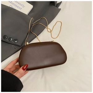 Detail of dark brown leather clutch bag with golden chain and round metal handle