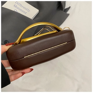 Detail of dark brown leather clutch with a matte gold semicircular metal handle