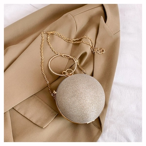 Gros plan sur le sac sphérique doré à paillettes avec sa poignée sertie de strass