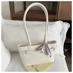 Detail einer weißen Ledertasche mit rosa karierter Schleife und Metallring-Akzenten