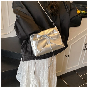 Detail of silver metallic PU crossbody bag featuring a large bow and chain strap