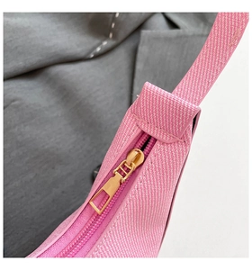 Detailed macro view of the gold metal zipper on a pink crescent underarm handbag