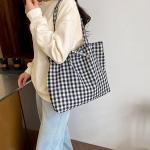 Retro black and white checkered tote bag with bow detail on a casual shoulder strap
