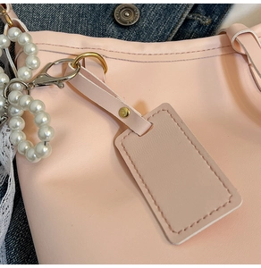 Detail of pink PU leather tote with white pearl charm and golden metal hardware