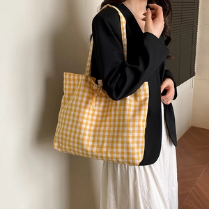 Chic yellow gingham tote bag with bow detail shown on a female model shoulder