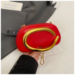 Close-up of red leather handbag featuring large gold C-shaped handle and fine metal chain strap