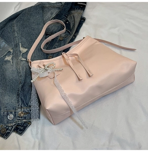 Close-up of light pink PU leather tote bag with pearl lace bow and long tassel details